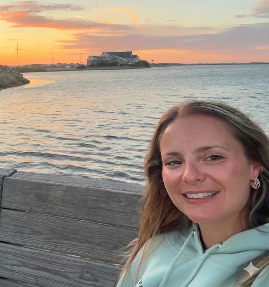 Emily Viynos with a sunset behind her, smiling