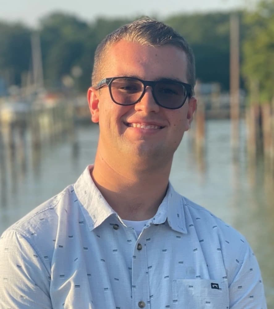 Logan posing on a dock with small boats in the background